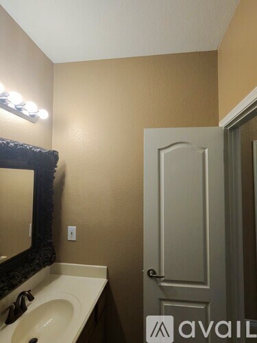A bathroom with a sink, mirror, and door.