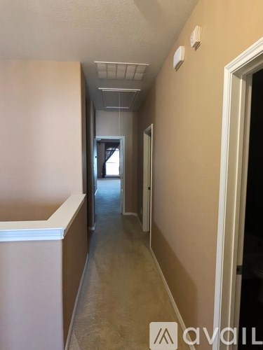 A hallway with a white ceiling and a door on the right.
