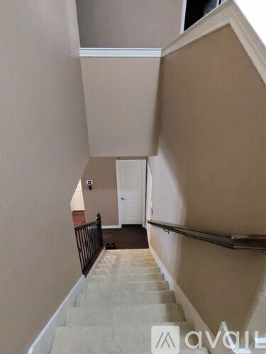 A staircase with a beige carpeted runner and a black railing.