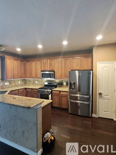 A kitchen with wooden cabinets and a stainless steel refrigerator.