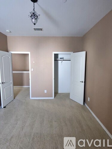 A room with a chandelier, two doors, and a carpeted floor.