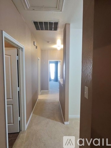 A hallway with a carpeted floor and white walls.
