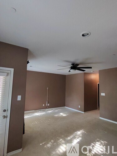 A room with a ceiling fan and a door.