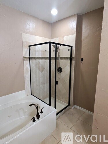 A bathroom with a white bathtub and a glass shower enclosure.