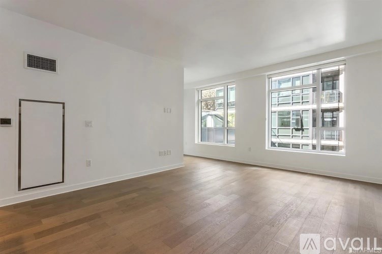 A spacious room with wooden flooring and a large window.
