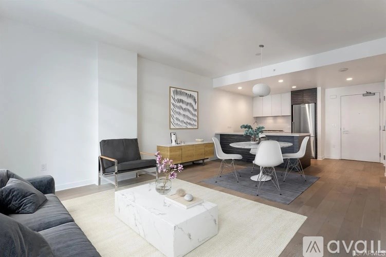 A modern living room with a grey sofa, a white coffee table, and a dining area in the background.