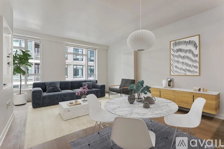 A living room with a white table and chairs, a grey sofa, and a large window with a view of a building outside.