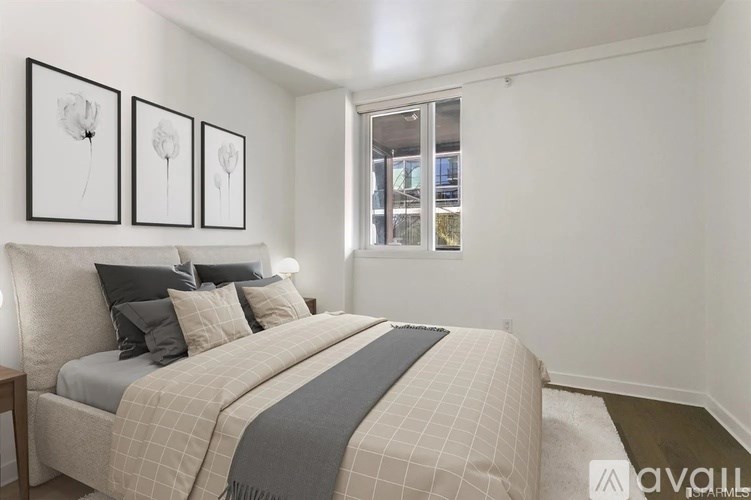 A bedroom with a bed, pillows, a blanket, and pictures on the wall.