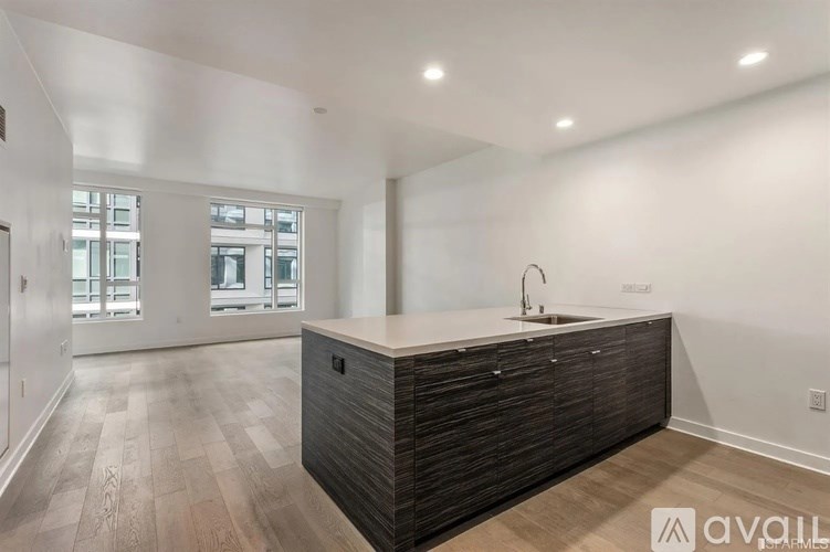A modern kitchen with a dark wood island and light wood flooring.