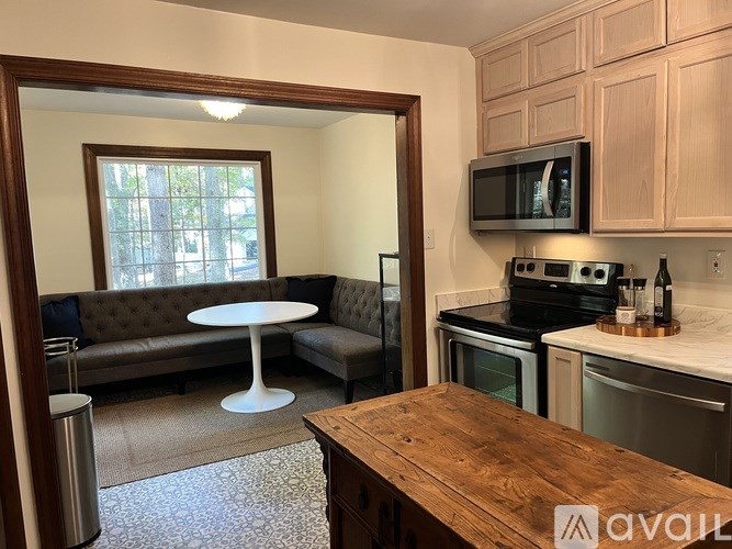 A kitchen with a wooden table and a couch with a window behind it.