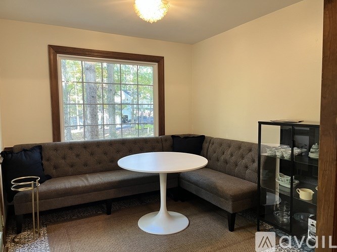 A living room with a grey couch, a white table, and a window.