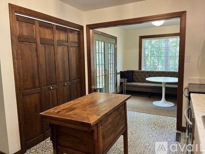 A wooden table sits in a room with a large mirror and a couch in the background.