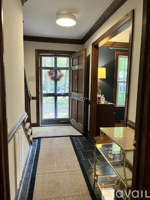 A hallway with a glass table and a carpeted floor.