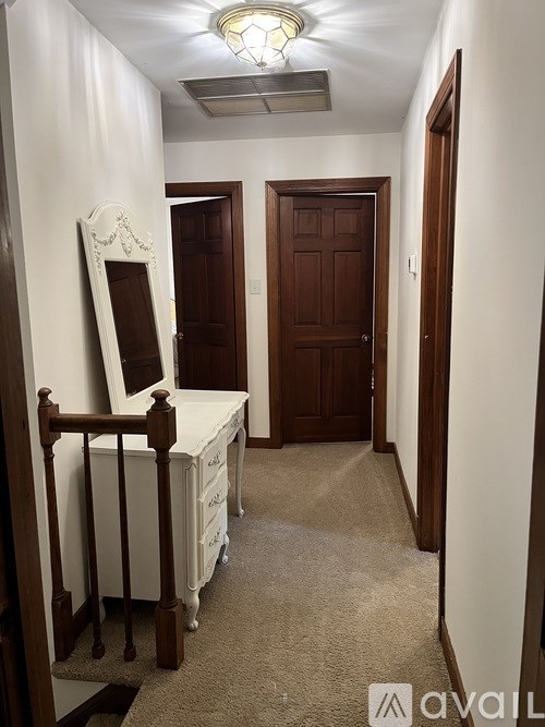 A bedroom with a white bed and a wooden dresser.