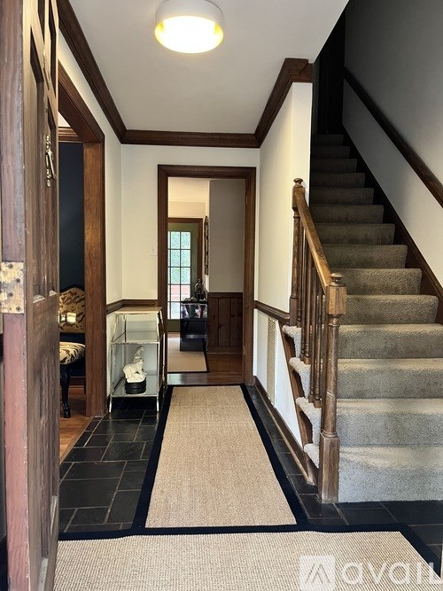 A hallway with a staircase and a door.