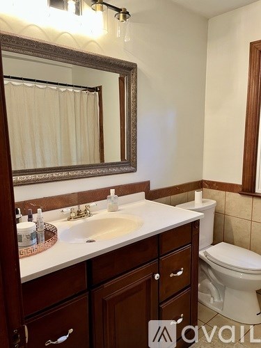 A bathroom with a white sink and brown cabinets.