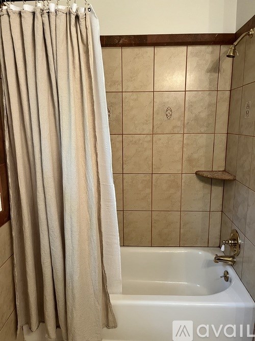 A beige shower curtain hangs over a white bathtub in a bathroom.