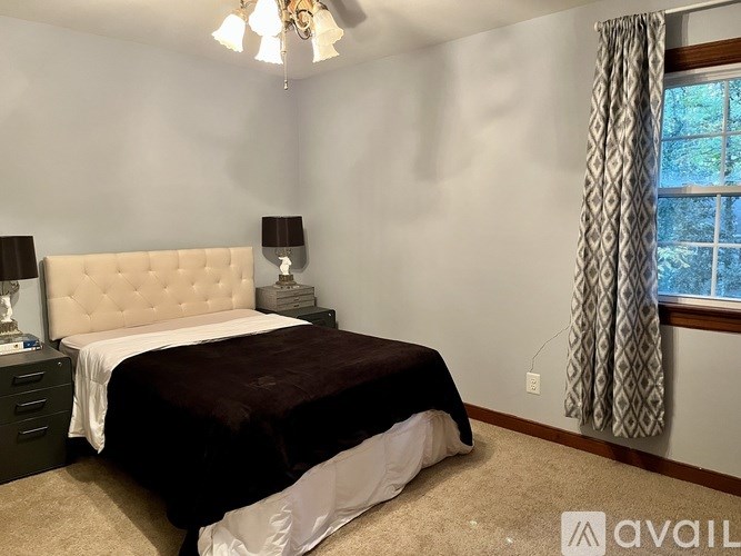 A bedroom with a large bed and a window with curtains.