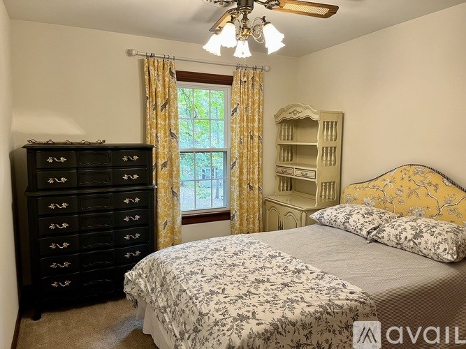 A bedroom with a bed, dresser, and window with curtains.