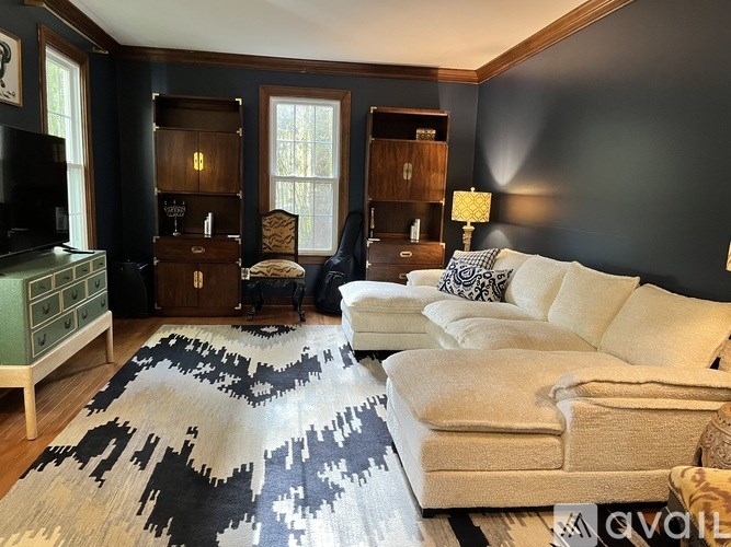 A living room with a black and white cowhide rug, a white couch, and a wooden cabinet.