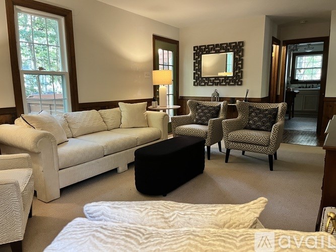 A living room with a white couch and a black ottoman.