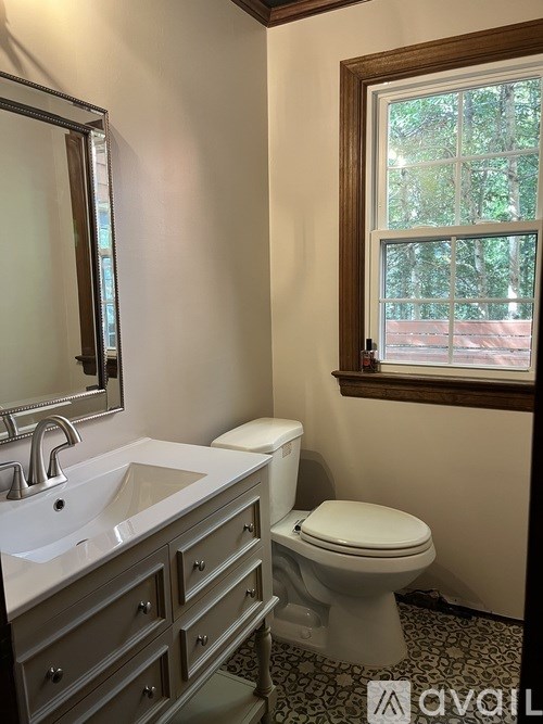 A bathroom with a toilet, sink, and mirror.