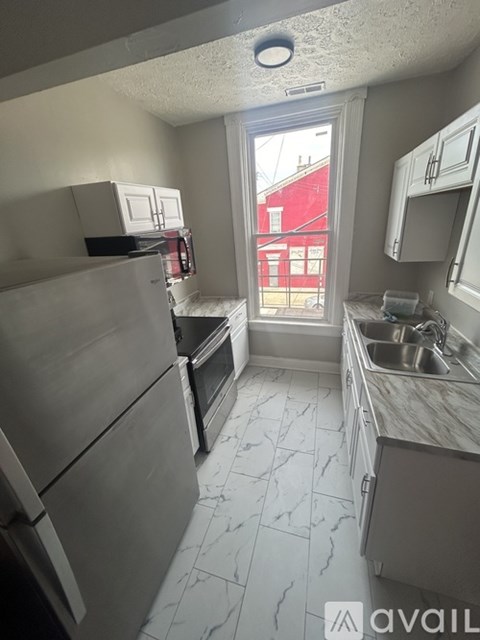 A kitchen with a refrigerator, microwave, and sink.