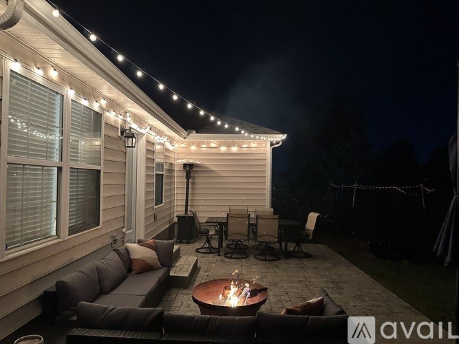 A cozy outdoor seating area with a lit fire pit and string lights.