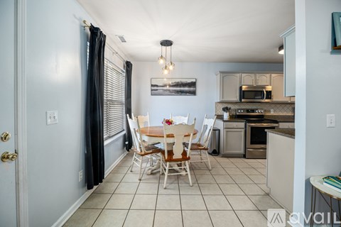 A kitchen with a dining table and chairs in the middle of the room.