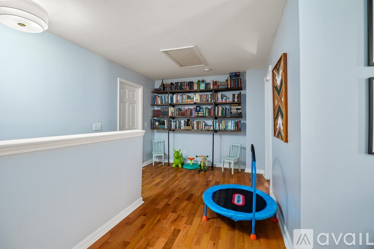 A room with a blue trampoline and a bookshelf filled with books.