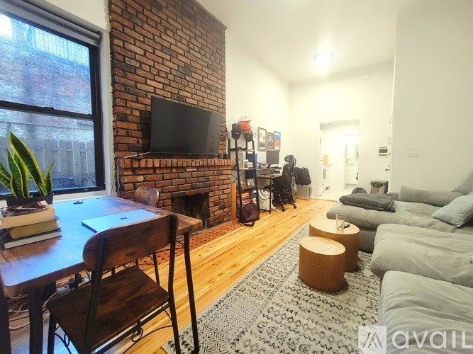 A living room with a brick fireplace and a grey couch.