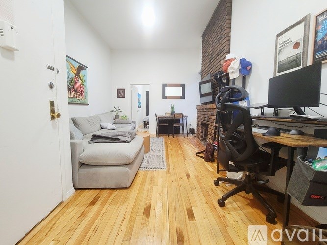 A room with a couch, chair, and desk with a computer.