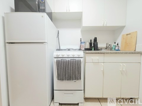 A white refrigerator is in a kitchen with a white oven and white cabinets.