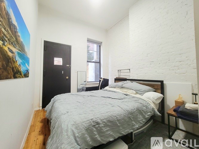 A bedroom with a bed, nightstand, and a painting on the wall.