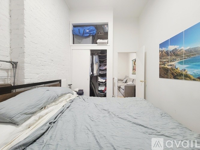 A bedroom with a bed, a wardrobe, and a painting of a beach scene on the wall.