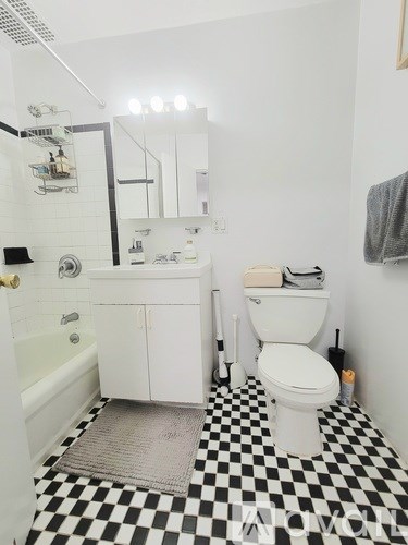 A white toilet sits next to a white sink in a bathroom with a black and white checkered floor.