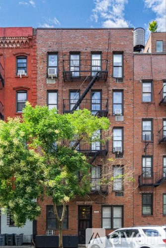 A red brick building with a tree in front of it.
