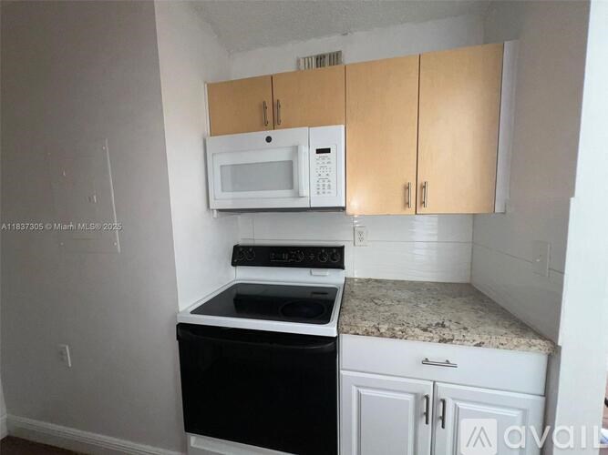 A kitchen with a black oven and white microwave.