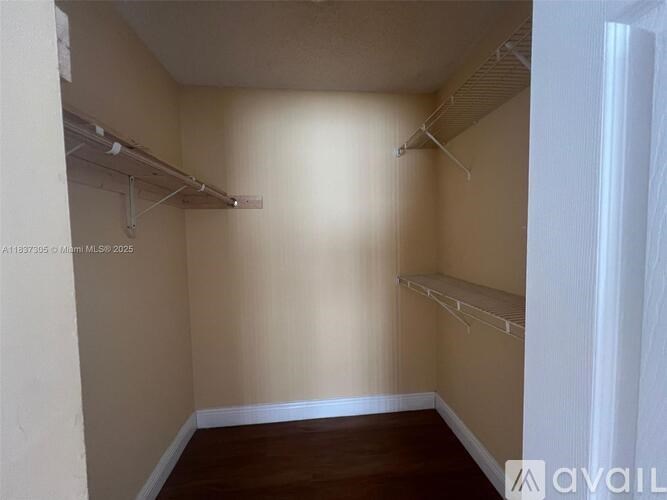 A small, empty room with a wooden floor and white walls.