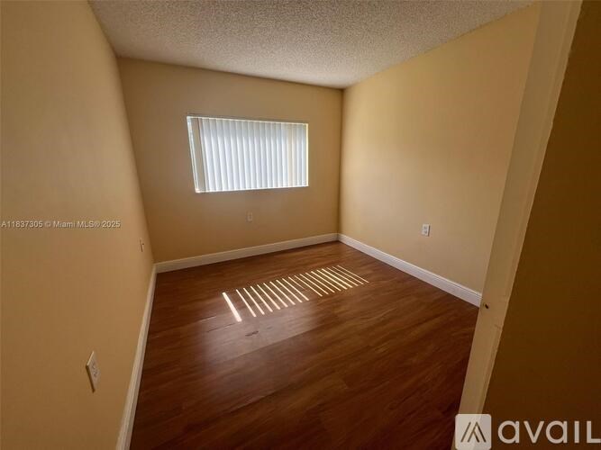 A room with wooden flooring and a window with blinds.