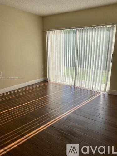 A room with wooden flooring and a window with blinds.