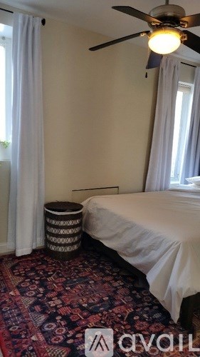 A bedroom with a bed, a fan, and a basket.