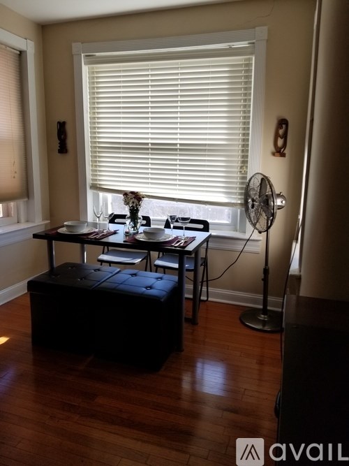 A room with a table, chairs, and a fan.