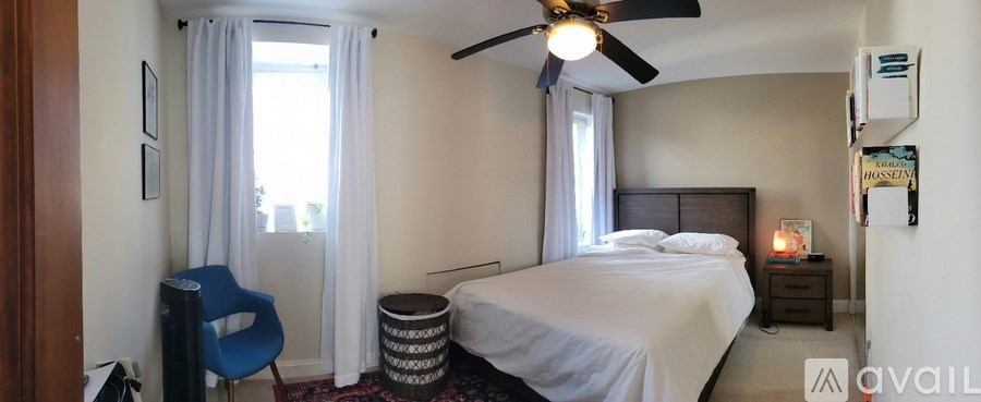 A bedroom with a bed, a ceiling fan, and a blue chair.
