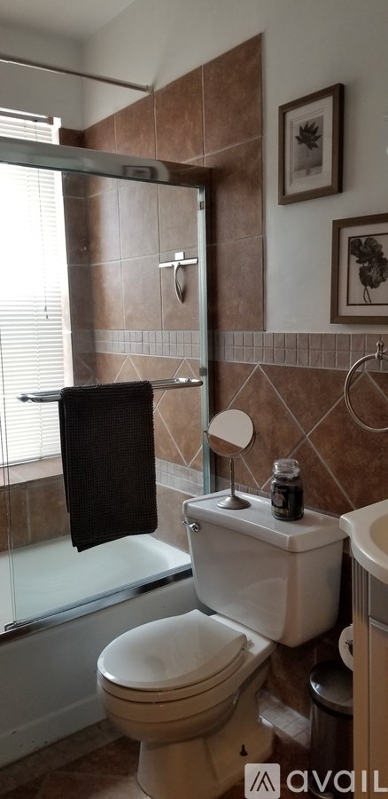 A bathroom with brown tiles and a white toilet.