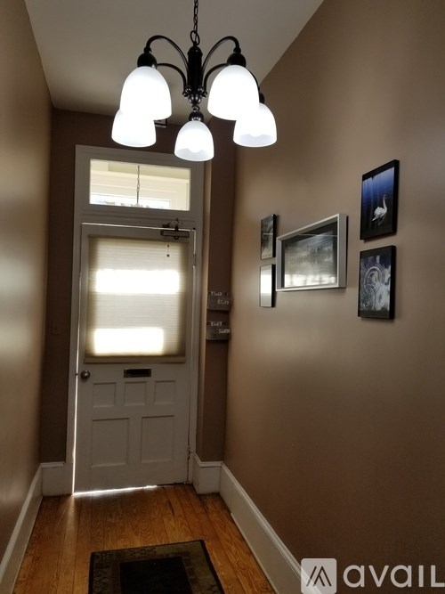 A hallway with a white door and a chandelier.