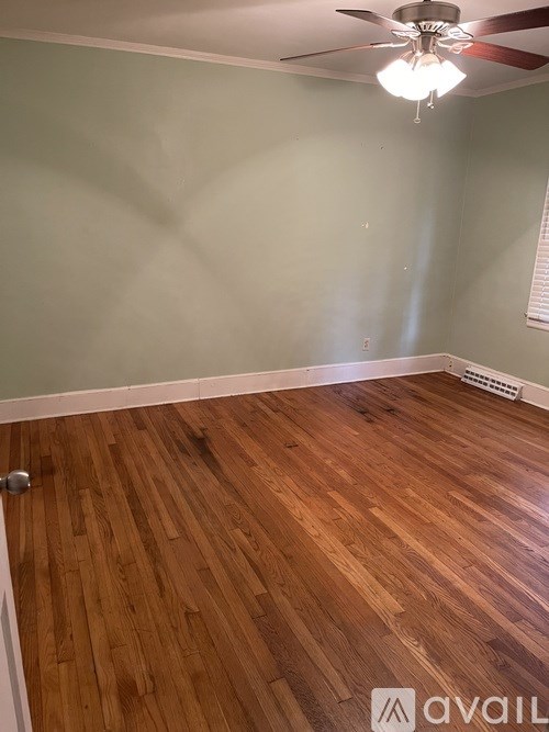 A room with wooden flooring and a ceiling fan.