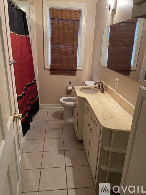 A bathroom with a toilet, sink, and mirror.