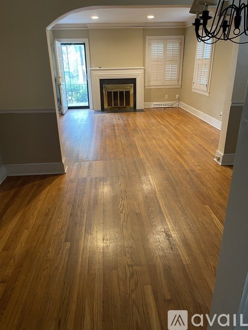 A room with wooden flooring and a fireplace.