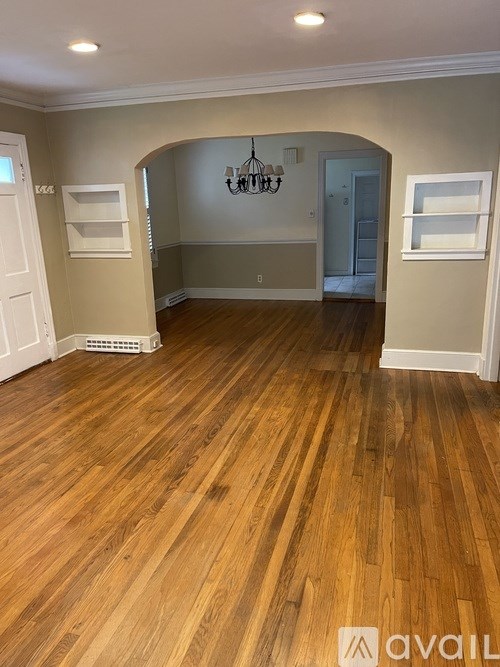 A room with wooden flooring and a chandelier.